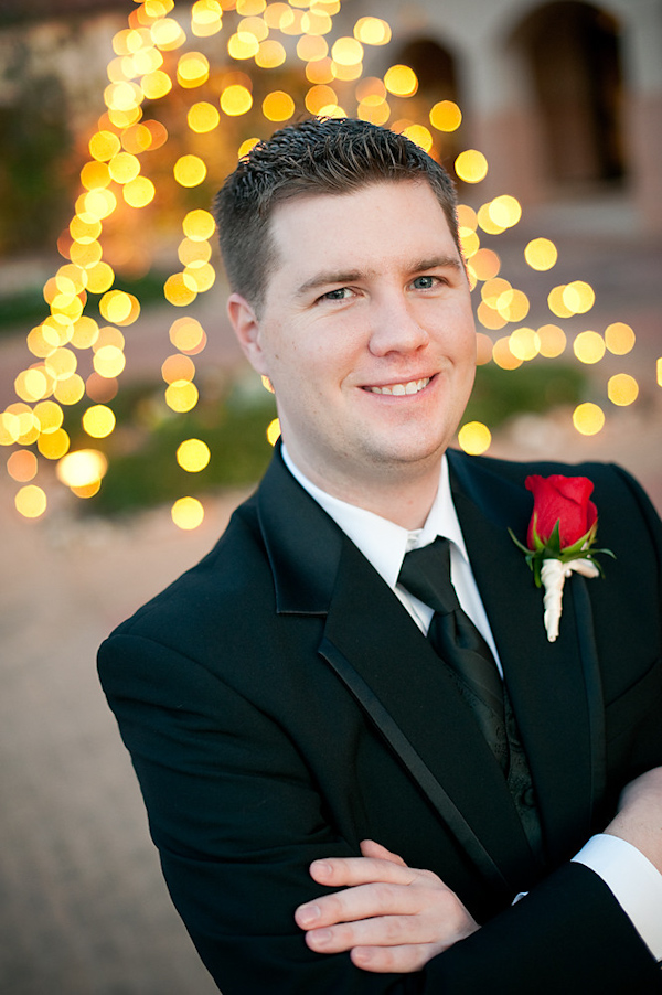 the handsome groom wearing a black suit and tie with a red rose boutonniere - photo by Houston based wedding photographer Adam Nyholt 